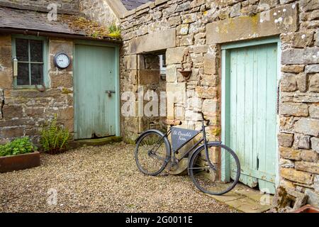 rustic old bicycle in stone courtyard at St Oswald's farm on Hadrian's Wall Northumberland Stock Photo