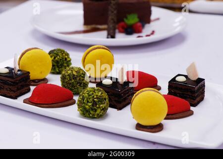 assorted french pastries in a platter as petit four with macaroons, chocolate cake, pistachio balls etc. Stock Photo