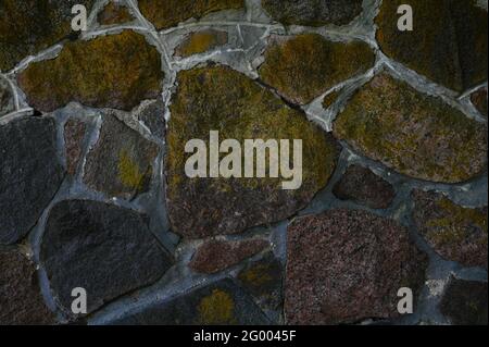 Old stone wall texture abstract background. Some of the stones have a yellow-brown coating. Stock Photo