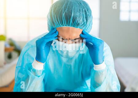 Tired exhausted doctor after long shift fighting against Coronavirus covid-19 at hospital clinic Stock Photo