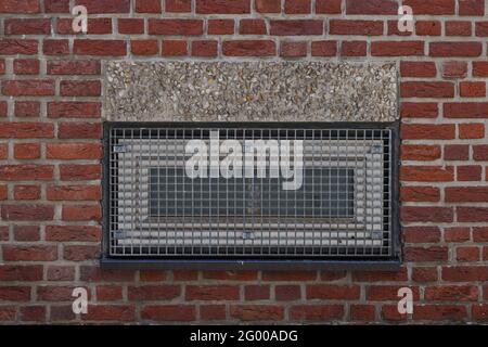 Exterior of metal rectangular windows with grating on rough brick wall. Stock Photo