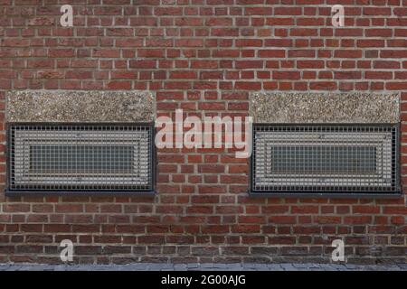 Exterior of metal rectangular windows with grating on rough brick wall. Stock Photo