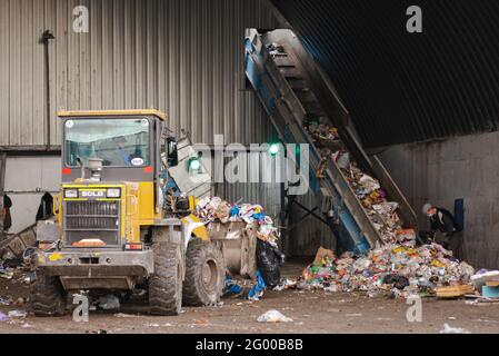 Moscow. Russia. October 2020. Garbage factory. The bulldozer brings the garbage to the conveyor belt. Stock Photo