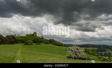 Eifel landscape with lone rock on green meadow with clouds of a summer thunderstorm above near Gerolstein Stock Photo