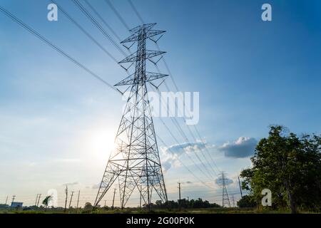High voltage electric transmission tower, high voltage post, High voltage tower near sunset blue sky background Stock Photo