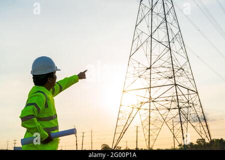 Asian an engineers working inspections at the electric power station to view the planning work by producing electricity high voltage electric transmis Stock Photo