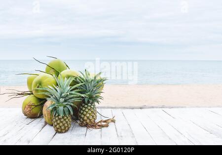 Summer background, coconuts and pineapples on white wood table, on the beach in summer Stock Photo
