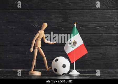 Wooden mannequin, Mexican flag and soccer ball on dark wooden background Stock Photo