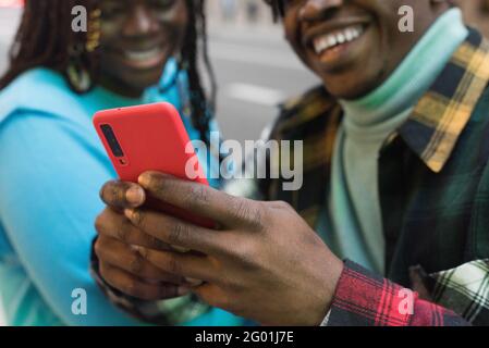 Smiling black couple looking at mobile on the street. Stock Photo