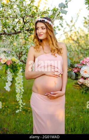 Happy pregnant woman in pink dress looking at sunrise. Pregnant woman Stock Photo