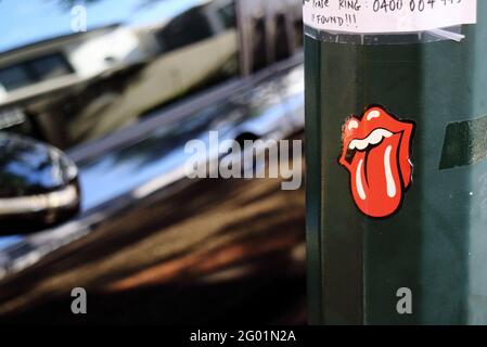 Rolling Stones Tongue and Lip logo sticker designed by John Pasche attached to a lamp pole with a car passing by in Brisbane Australia. Stock Photo