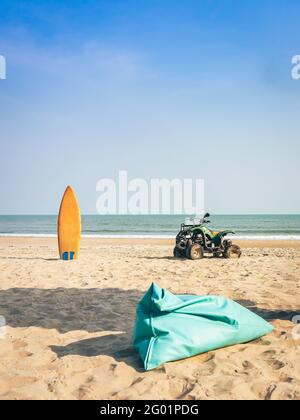 Vintage green ATV on the sandy beach. Quad ATV all terrain vehicle parked on beach, Motor bikes ready for action with summer sun flaring on bright day Stock Photo