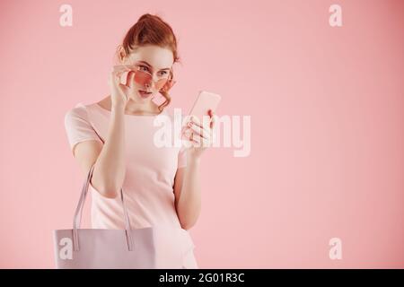 Shocked emotional young woman taking off glasses and reading notification or text message on smartphone Stock Photo