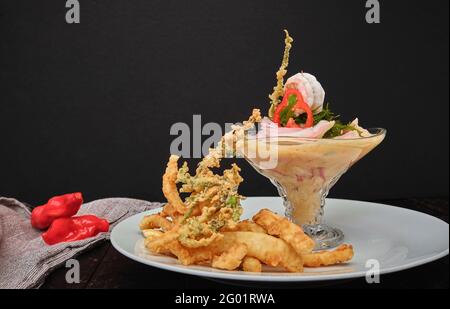 Peruvian food: called 'Leche de tigre' and 'chicharron', peruvian fresh fish on glass (Raw fish cocktail ceviche with lime, grinder, chili and cilantr Stock Photo