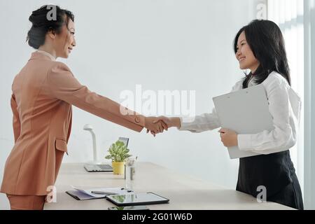 Smiling young job applicant and company Human Resources manager shaking hands Stock Photo
