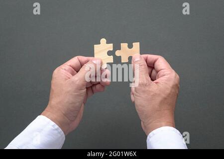 Two hands holding jigzaw puzzles, business matching, finding the right fit concept. Stock Photo