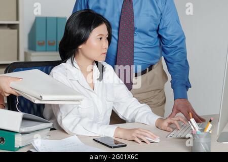 Businesswoman working on laptop when colleagues giving more tasks that have to be done Stock Photo