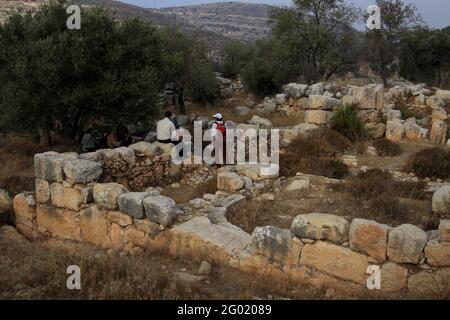 Hikers, senior adults, on a weekend hike rest in the ruins of a Byzantine 6th century AD Saint Theodoros Church, Beit Sila, Judean Hills, West Bank. Stock Photo