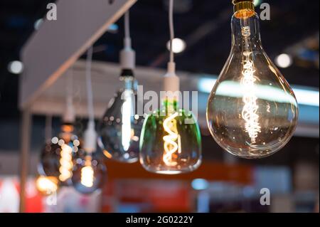 Many differently shaped incandescent bulbs are suspended in the dark Stock Photo