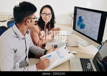 Young positive entrepreneurs analyzing charts and reports when working on strategy of development Stock Photo