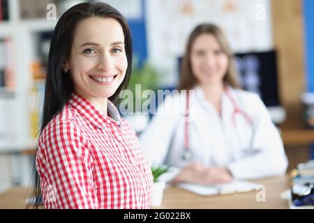 Smiling young woman patient on background of doctor in medical office Stock Photo