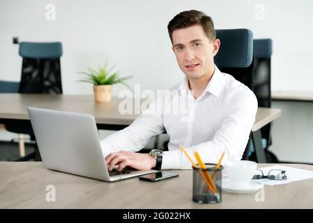 Businessman in office. Employee sitting on a chair and working with laptop Stock Photo