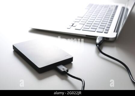 External USB disk, hard disk drive connected to laptop Stock Photo