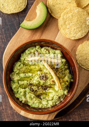 Bowl of guacamole with tortilla chips on wooden background Stock Photo