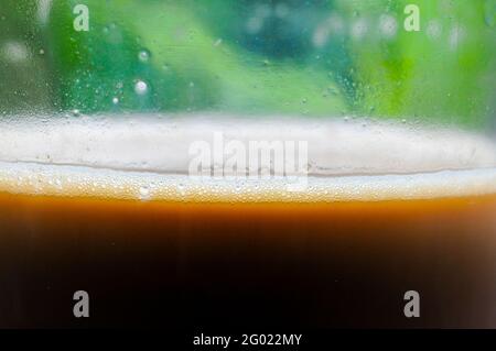Close up of coffee in a glass on a green leaf background