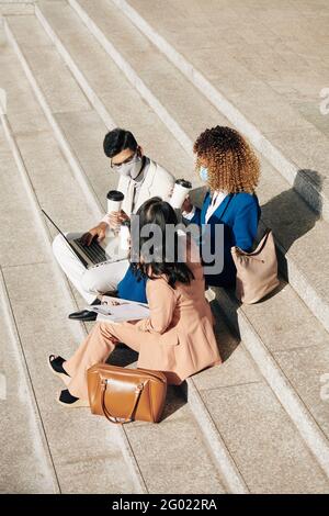 Business people having outdoor meeting, they are drinking take out coffee and discussing project presentation they are working on Stock Photo