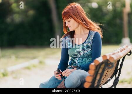 Pensive woman in a park holding her sunglasses on a sunny day. American shot. Stock Photo