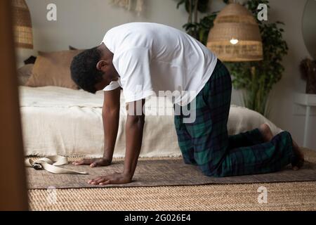 Sporty muscular young african man working out, yoga, pilates, fitness training, doing Cat Pose Stock Photo