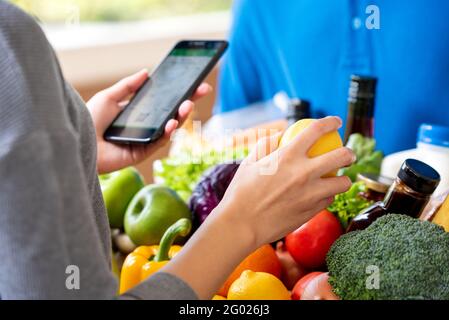 Customer checking grocery that ordered online and delivered by deliveryman at home, food delivery service concept Stock Photo