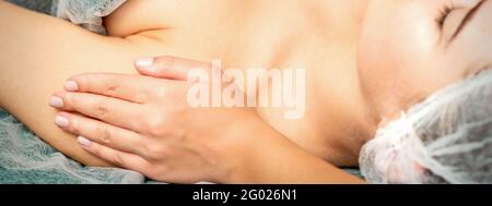 Side view hands of female therapist making massage of shoulders to young caucasian woman in spa beauty salon Stock Photo