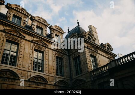 Low angle shot of a brown building with large windows under the clouds