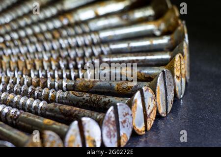 Rusty scattered screws lying on ground. Metal industry Stock Photo