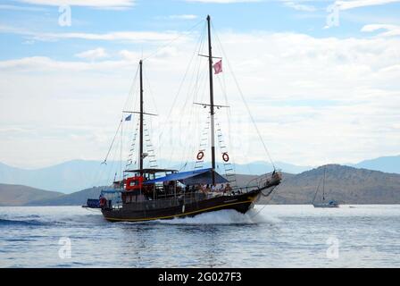 Two-masted vessel, flying the Greek flag, at sea offshore from Corfu, Greece with the coast of Albania in the background Stock Photo