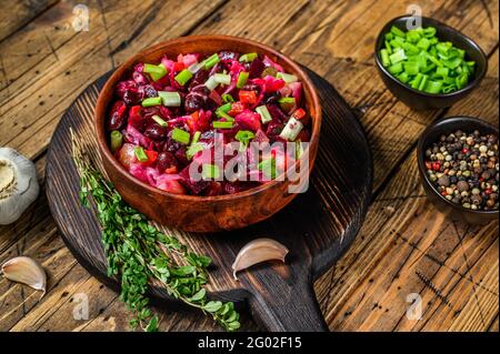 Traditional russian salad vinaigrette with boiled vegetables, pickled cucumbers in bowl . Wooden background. Top view Stock Photo