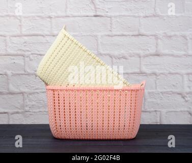 stack of plastic empty laundry baskets on wooden blue table. White brick wall background Stock Photo