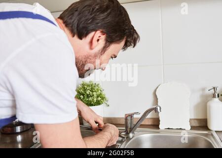 Professional plumber or do-it-yourselfer connecting the kitchen faucet to the sink Stock Photo