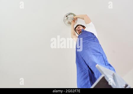 Do-it-yourself or electrician installs new lamp with energy-saving lamps on the ceiling Stock Photo