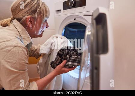 Housewife in front of tumble dryer or washing machine in the bathroom for cleanliness and hygiene Stock Photo