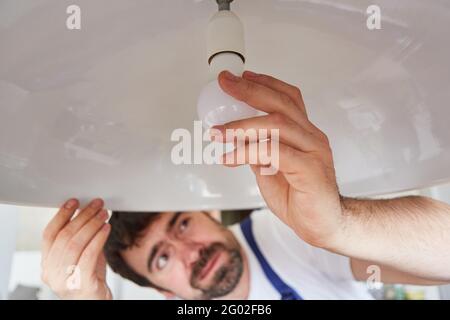 Do-it-yourselfers or craftsmen exchanges defective lightbulbs on the ceiling lamp Stock Photo