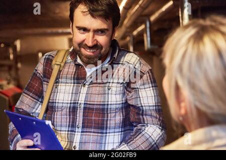 Craftsman with checklist in conversation with a customer in the boiler room after maintenance Stock Photo