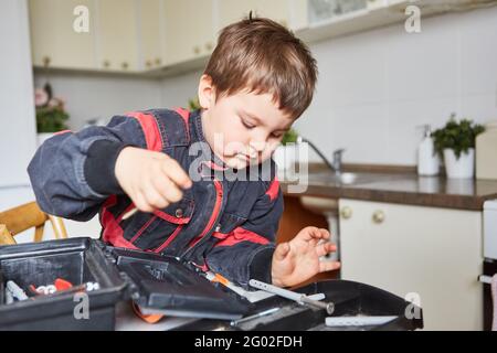 Boy is looking for tools in the toolbox while handyman playing in the kitchen Stock Photo