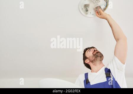 Do-it-yourselfers or electricians assemble a ceiling light with energy-saving lamps Stock Photo