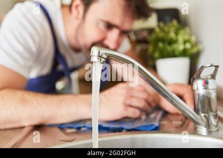 Craftsman as plumber repairs mixer tap on the tap in the kitchen sink Stock Photo
