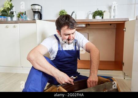 Craftsman or DIY enthusiast is looking for tools to repair a kitchen sink Stock Photo