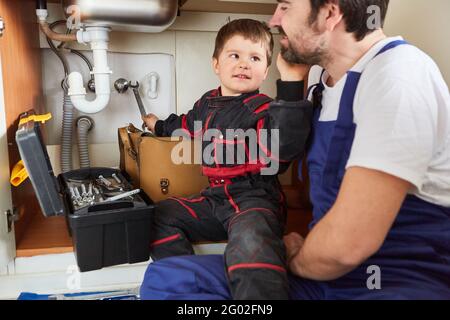 Child helping his father, a handyman, repair the sink in the kitchen Stock Photo