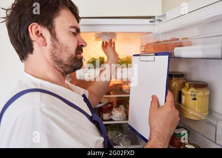Craftsman with checklist checks the lighting in the refrigerator to save energy Stock Photo
